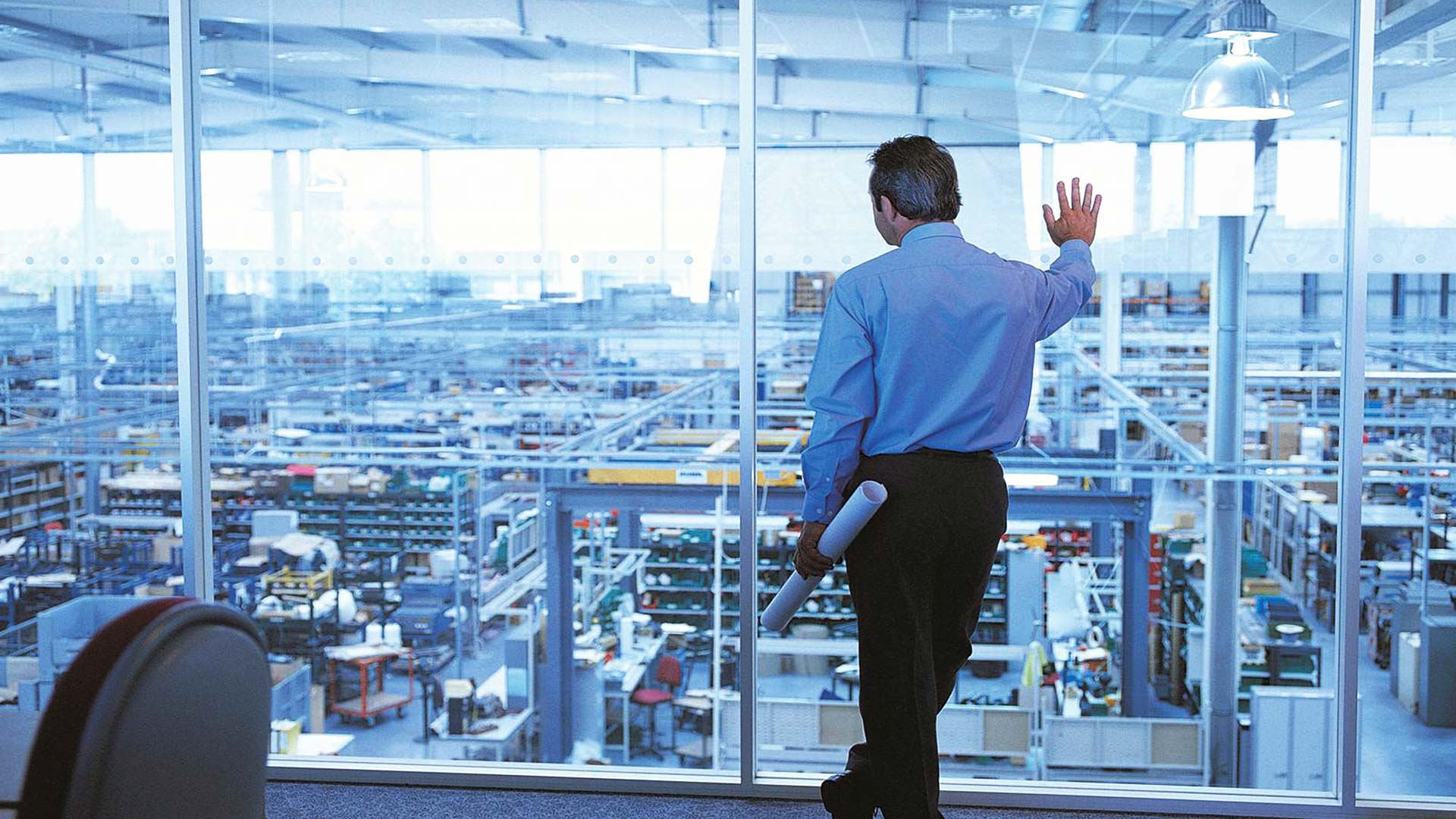 Guy staring down into factory leaning against wall